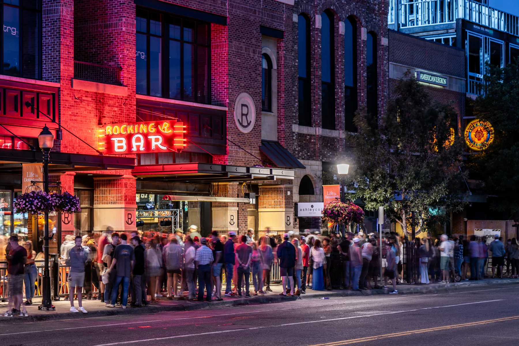 People gathering along Main Street outside the Rocking R Bar in downtown Bozeman at dusk