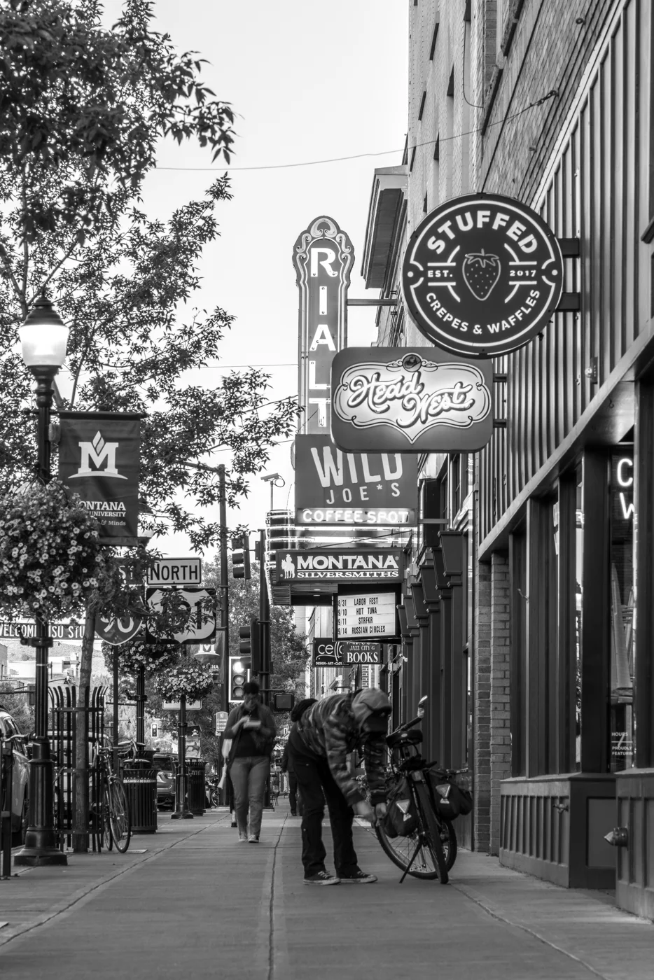 People walking beneath the Rialto and other historic signs along Main Street in Bozeman