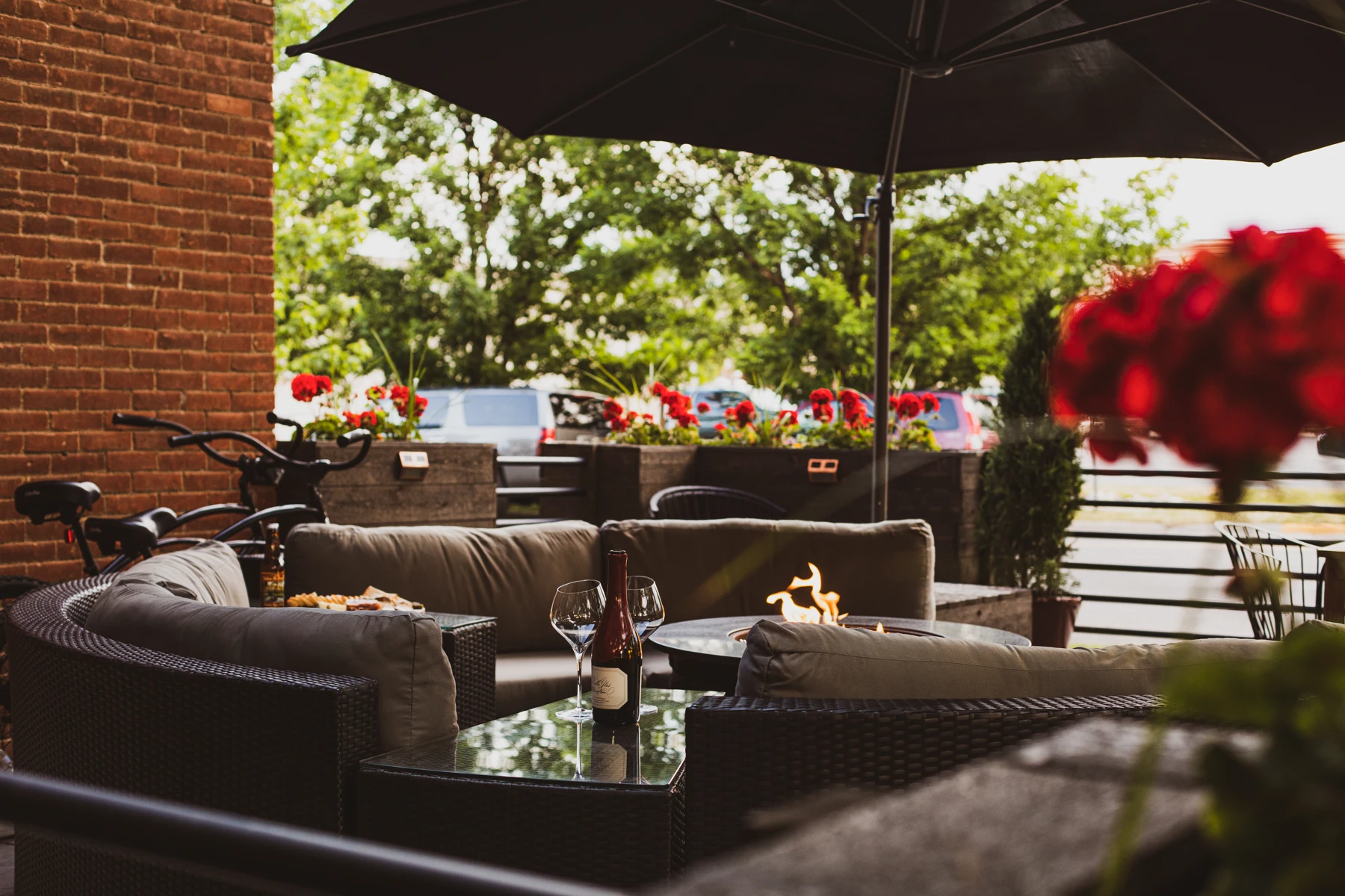 A wide view of Loft503’s brick-lined patio with lounge seating, flowers and cruiser bikes